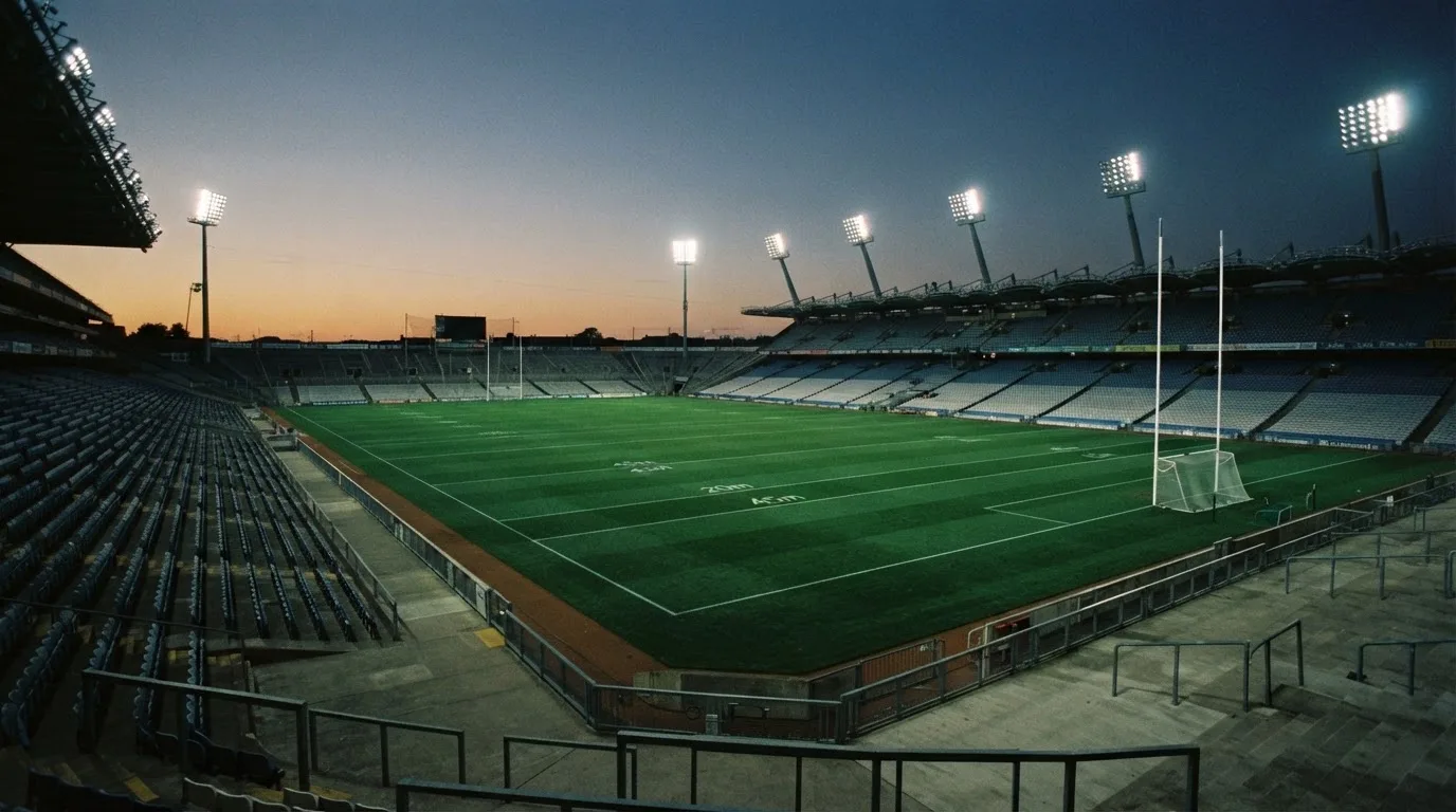 An empty football stadium with floodlight masts at dusk