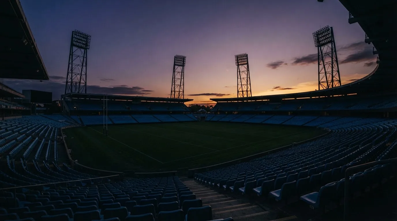 An empty football stadium with floodlight masts at dusk