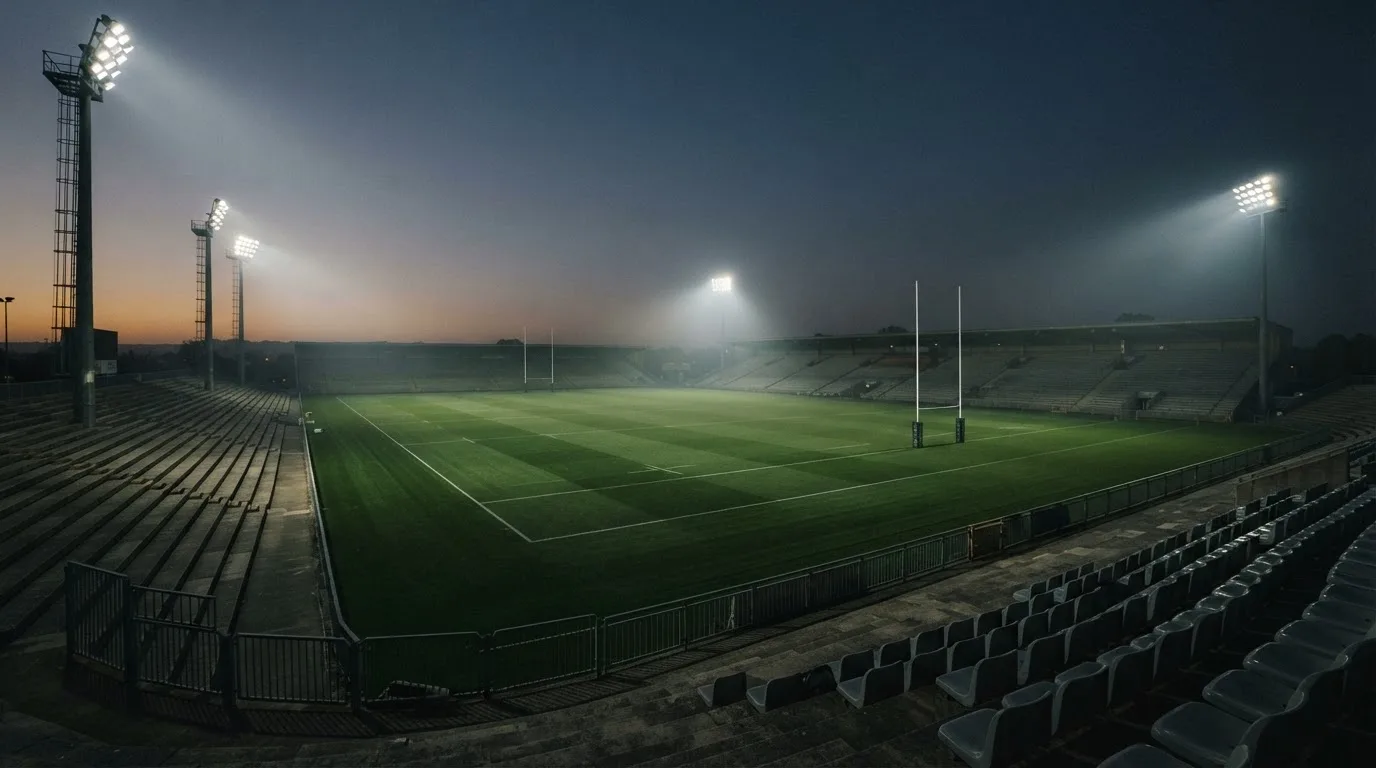 An empty football stadium with floodlight masts at dusk
