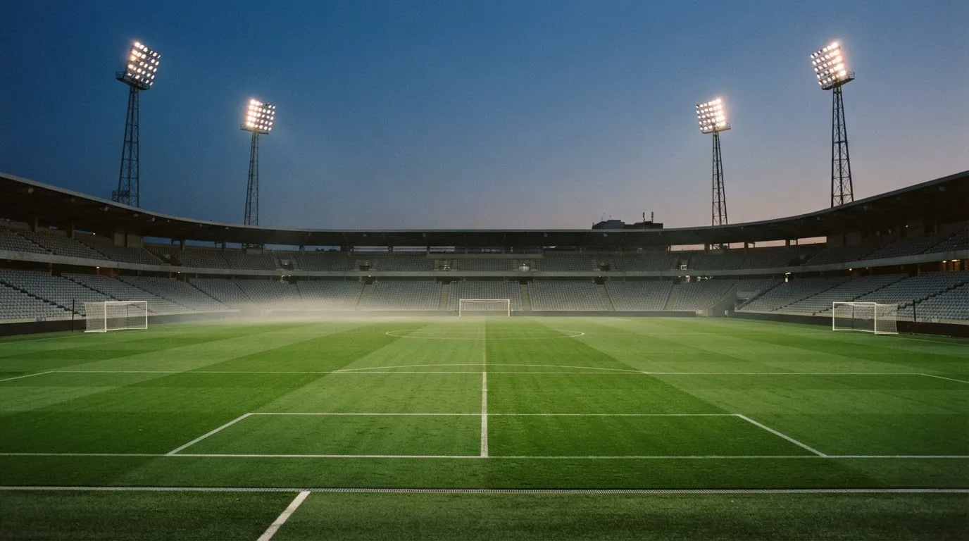An empty football stadium with floodlight masts at dusk