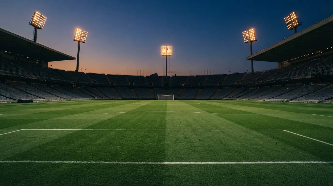 An empty football stadium with floodlight masts at dusk