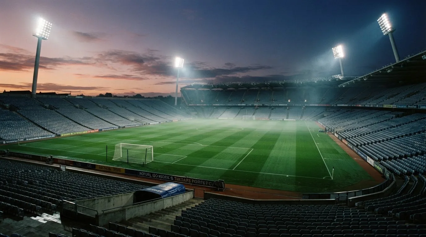 An empty football stadium with floodlight masts at dusk