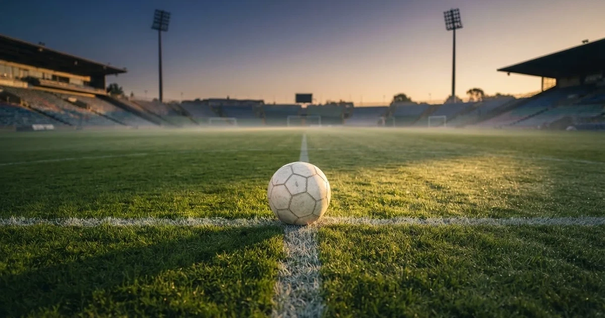 A ball on the centre spot of a grass pitch in morning light