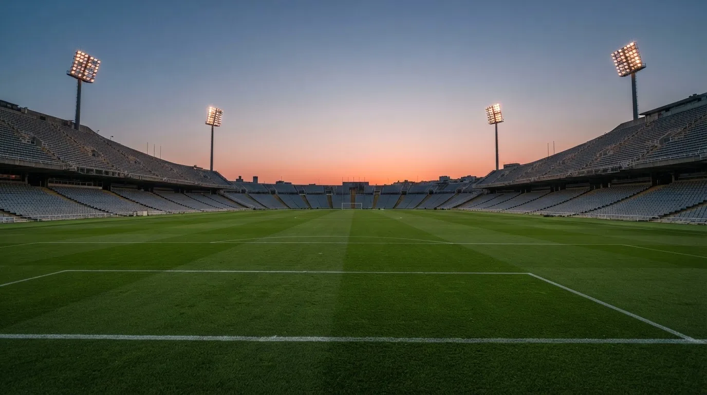 An empty football stadium with floodlight masts at dusk
